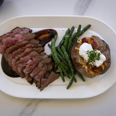Flank steak with stuffed baked potato and green beans.