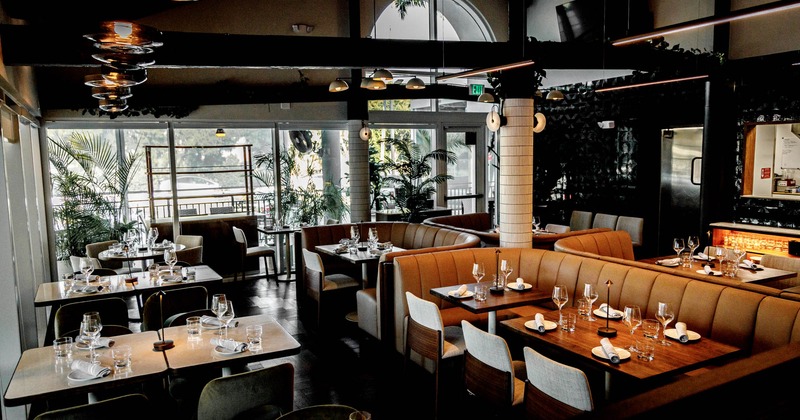 Interior of a modern restaurant with tables, booths, and large windows