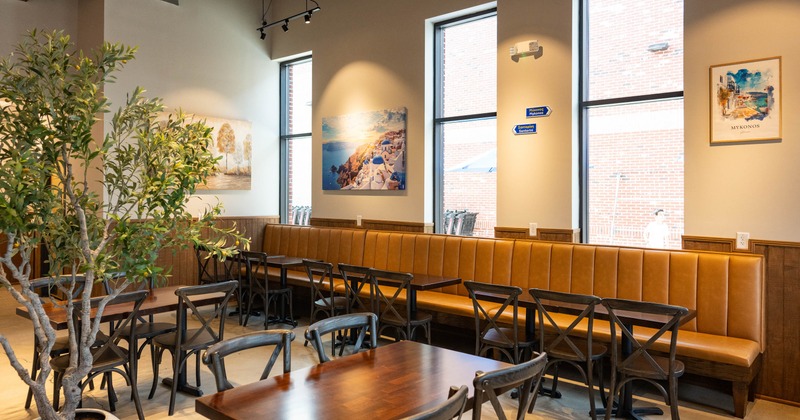 Interior- bench seating, tables, chairs, featuring large windows and artwork on the walls.