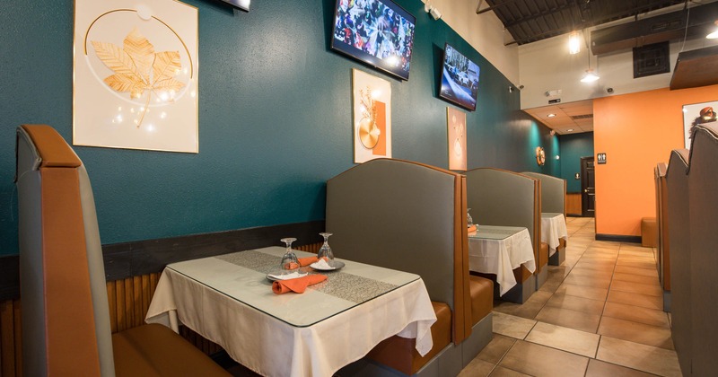 Interior of a modern restaurant with seating booths, white tablecloths and decorative wall art