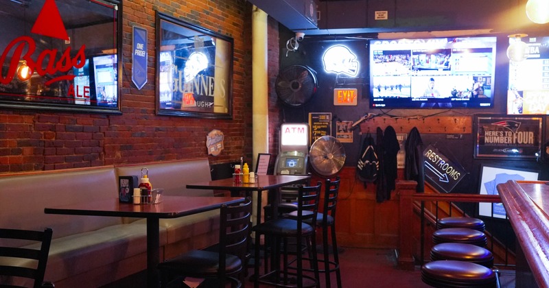 Interior of a bar with red brick walls, sports signage, high seating, TVs