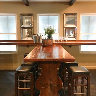 A bar nook with bar chairs, a table, bucket of drinks, glasses, and flowers on it.