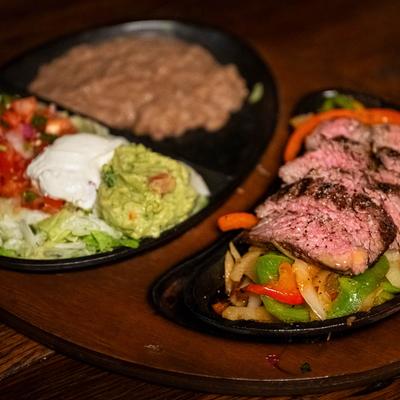 Wood fired grilled fajitas served with refried beans, pico de gallo, sour cream, guacamole.