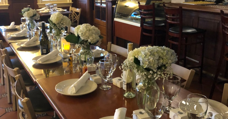 Long dining table set with flower arrangements, glasses and plates