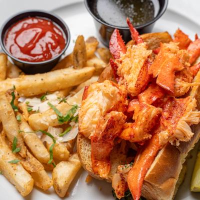Lobster roll served with fries and dipping sauces.
