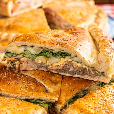 Stuffed pie, with chopped meat, lettuce, tomato, mozzarella, and American cheese.