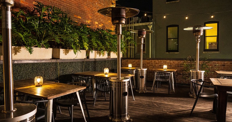 Patio at night with tables and chairs and patio heaters