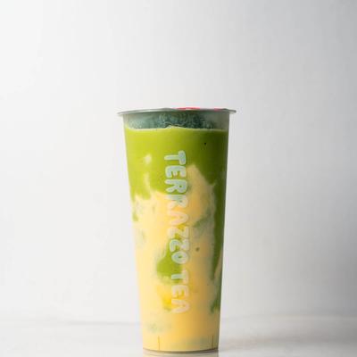 A tall cup of Terrazzo Tea with vibrant layers of green and yellow, set against a plain background.