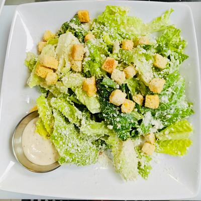 Caesar Salad topped with croutons and served with dressing on the side.