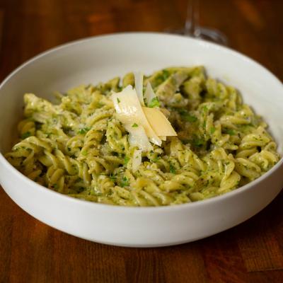 Fusilli in pesto sauce topped with shaved Parmesan cheese.