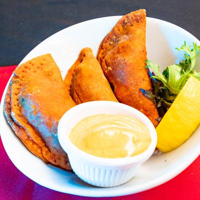 Fried empanadas served with dipping sauce and lemon.