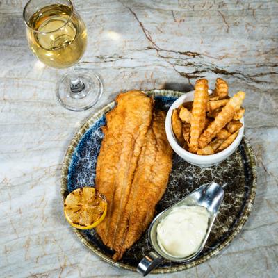 Fried catfish served with dipp, fries and a glass of white wine.