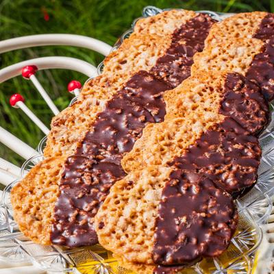 Chocolate-dipped lace cookies arranged on a glass serving tray.