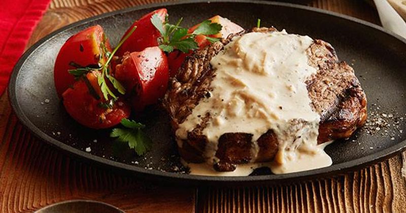Steak with sauce served with cherry tomatoes