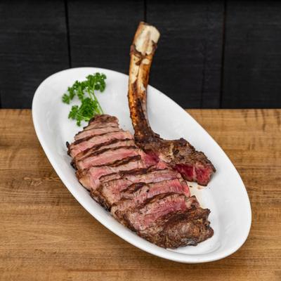 Sliced bone-in tomahawk steak with a rib bone left intact.