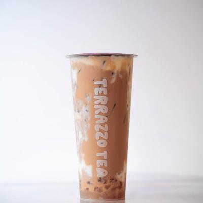 A tall plastic cup of iced milk tea with brown and cream swirls, labeled Terrazzo Tea.
