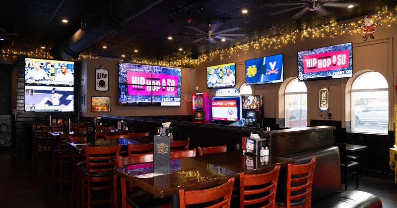 Interior, tables and chairs ready for guests, tv screens on the walls