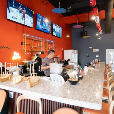 The bar featuring stools, TVs, and colorful paper lanterns and umbrellas decor.