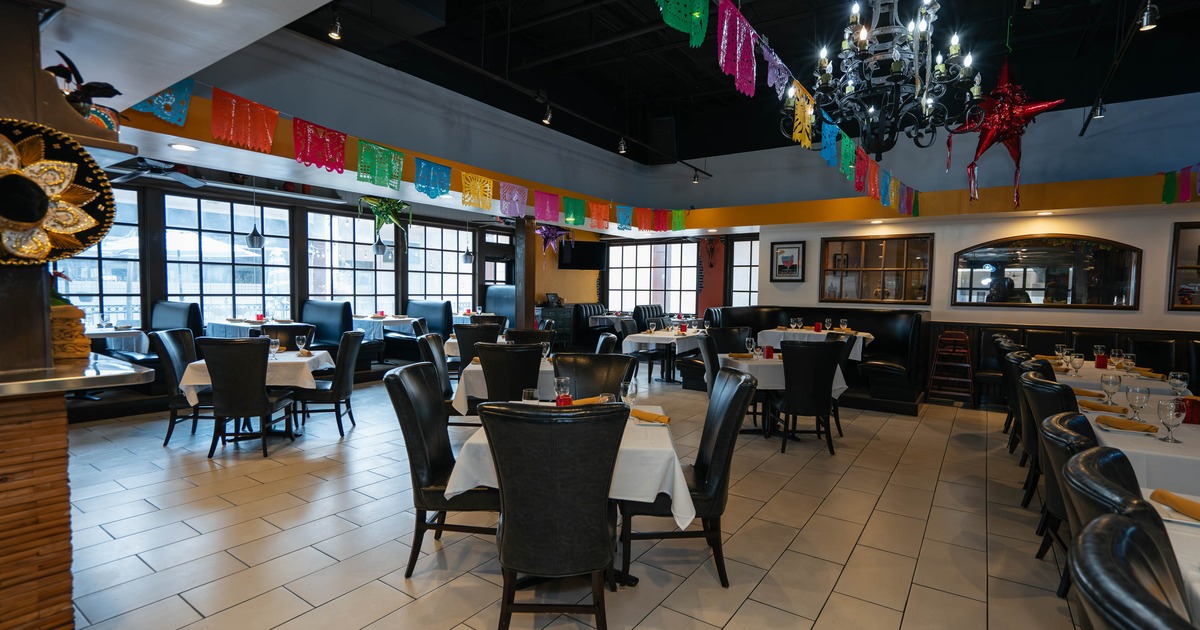 Interior of a restaurant with white tablecloths, dark chairs