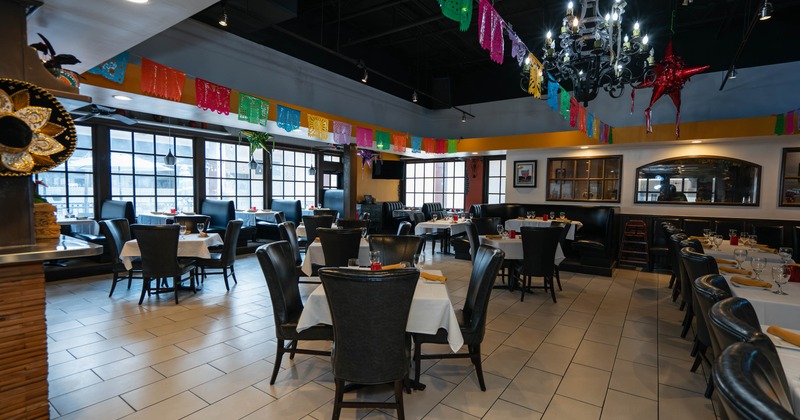 Interior of a restaurant with white tablecloths, dark chairs