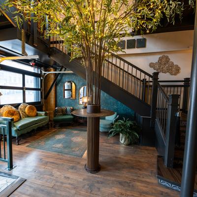 Interior, lobby lounge area under a staircase with a decorative tree.