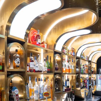 Close view at the bar whit stocked shelves, two beer taps and a small sink area.