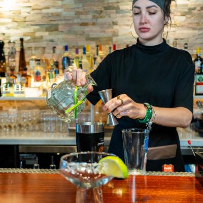 Bartender preparing a cocktail behind the bar.