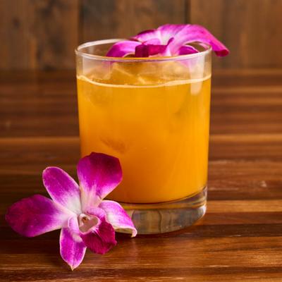 Cocktail in a rocks glass, garnished with a purple orchids.