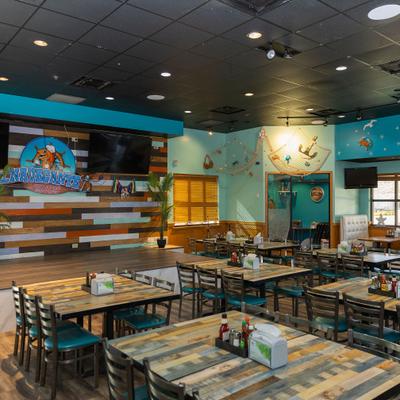 Dining room with turquoise chairs, wood tables, and wall murals.