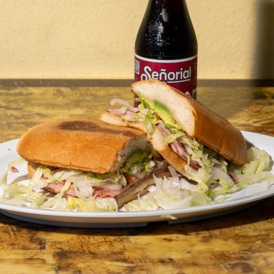 A plate holds Ham and cheese Torta on a wooden table, accompanied with a bottle of soda.