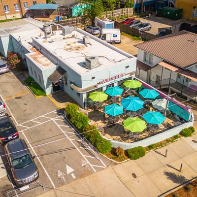 Aerial view of the restaurant with a paved parking lot and an outdoor seating area.