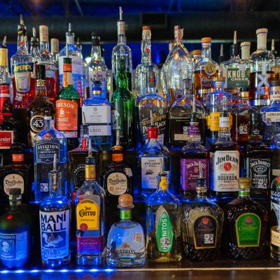 Assorted liquor bottles on blue-lit shelves.