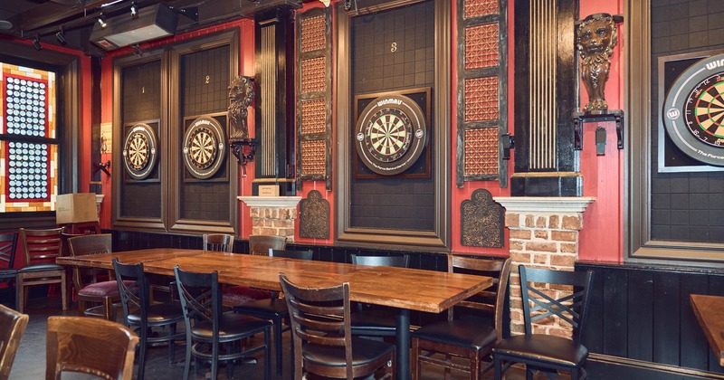 The interior featuring multiple darts boards and a large communal wooden table