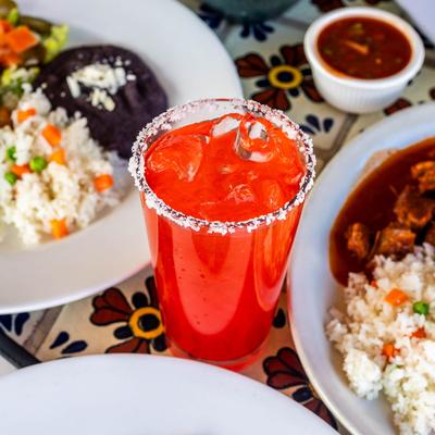 Vampiro cocktail surrounded by dishes with rice.