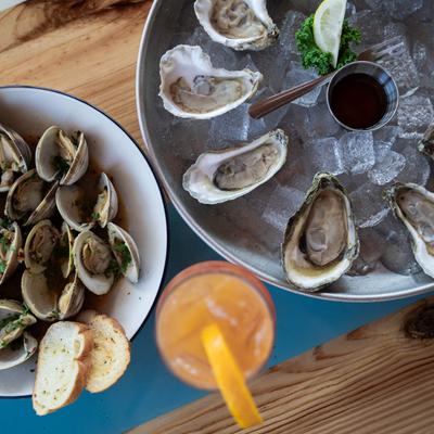 Clam and oyster plates with an orange drink, top view.