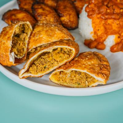 Beef empanadas served with fried sweet plantains, rice, and beans.