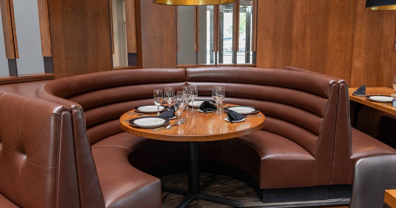 Interior, set round table and curved brown leather seating
