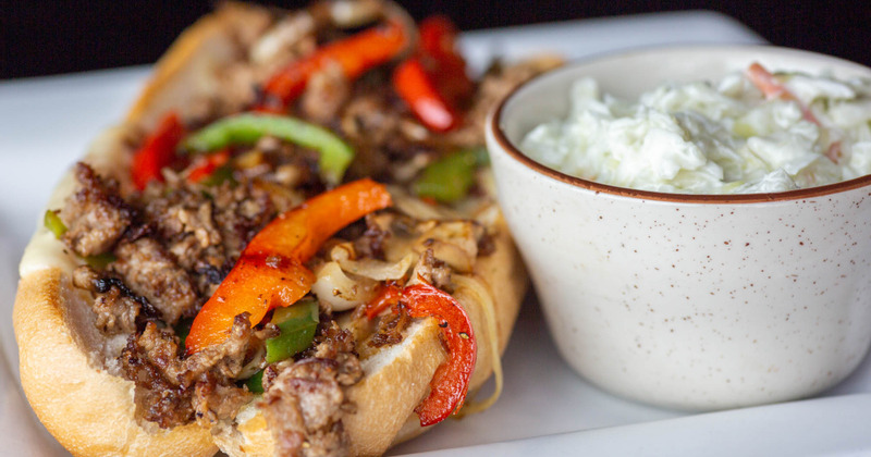 Philly Cheese-steak and a bowl of coleslaw with a salad dressing, closeup