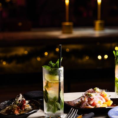 Mojito and appetizers on table with candles in the background.