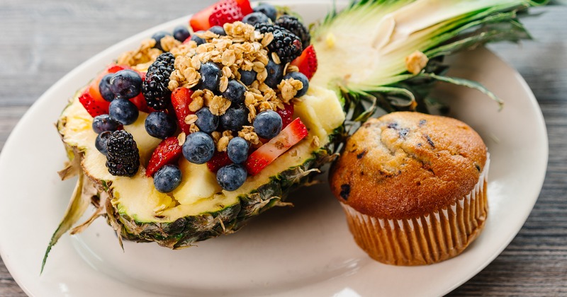 Hawaiian Parfait served inside a hollowed-out pineapple, paired with a muffin