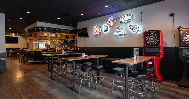 Spacious bar with wooden floors, high tables, and stools