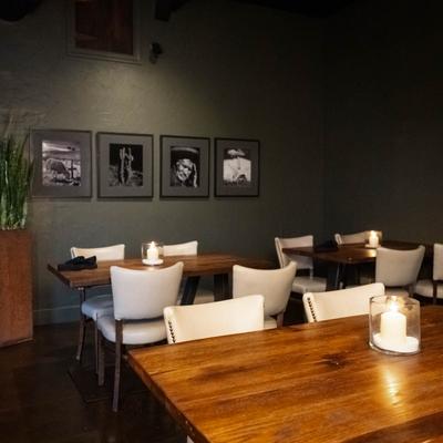 Interior, tables with candle light and chairs in front of a wall decorated with pictures.