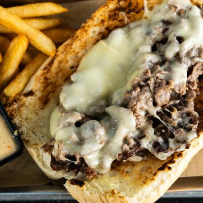 Cheesesteak sandwich served with a side of fries, close-up.