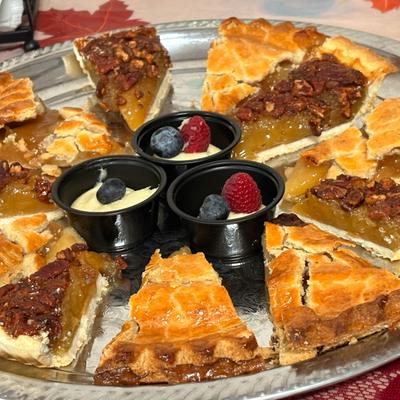 Assorted pie slices and mini berry-topped dessert cups arranged on a tray.