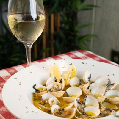 Steamed clams in a garlic butter sauce with lemon wedges, served with white wine.