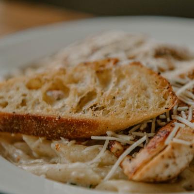Chicken pasta with a slice of toasted bread.
