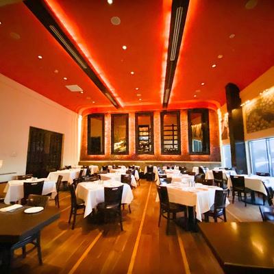 Elegant dining room featuring wooden floors and tables set with white tablecloths.