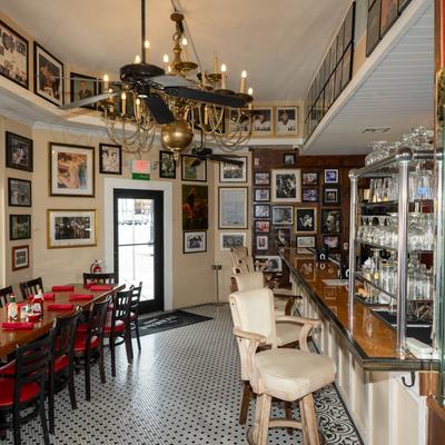 Interior with framed pictures, tables, chairs, and a bar.