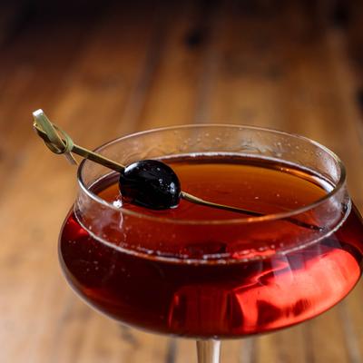 Manhattan cocktail served in a coupe glass and garnished with a cherry.
