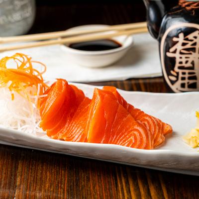 Salmon sashimi served with shredded carrot, daikon radish, pickled ginger, and wasabi.